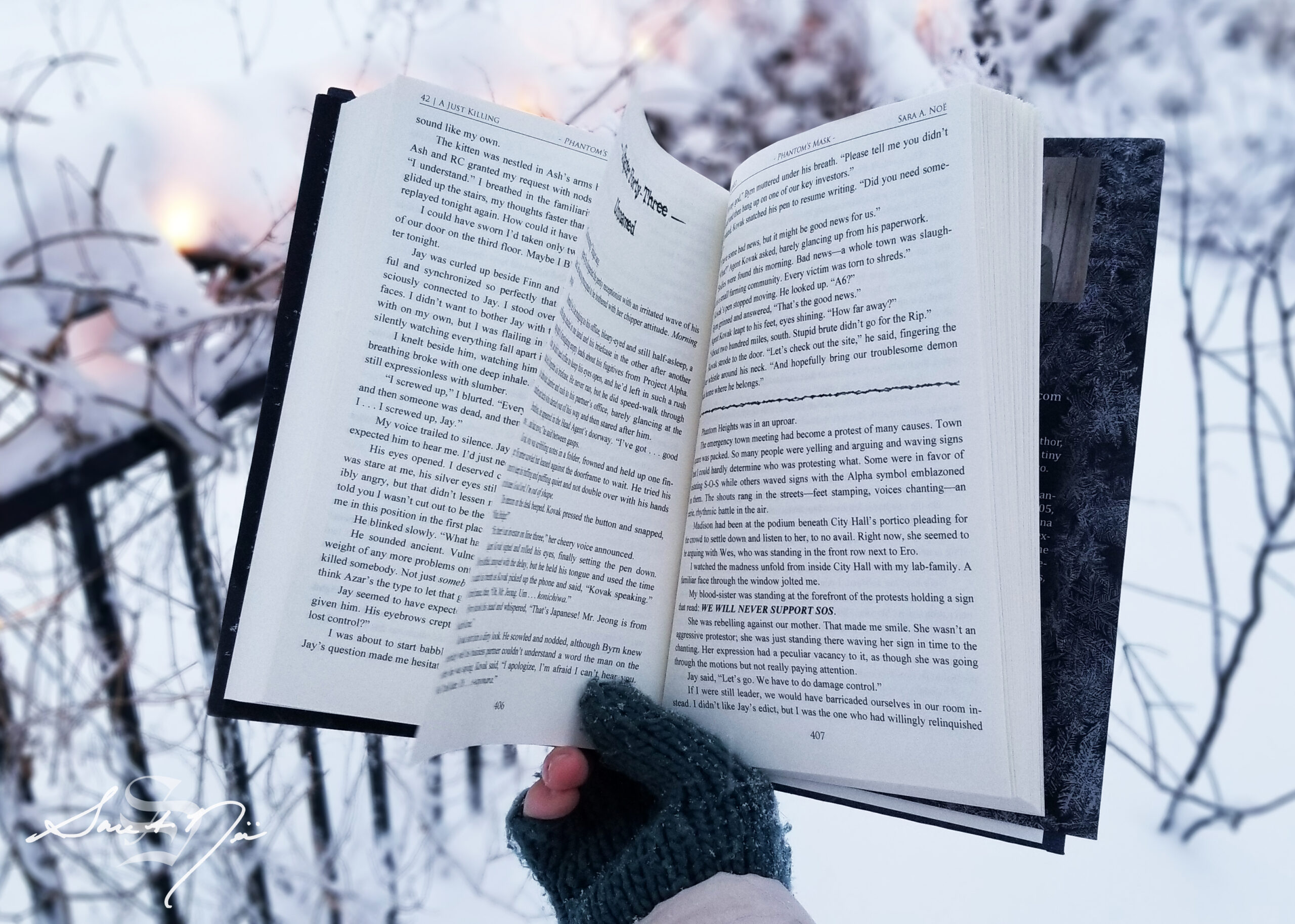 holding an open book in the snow with Christmas lights in the background