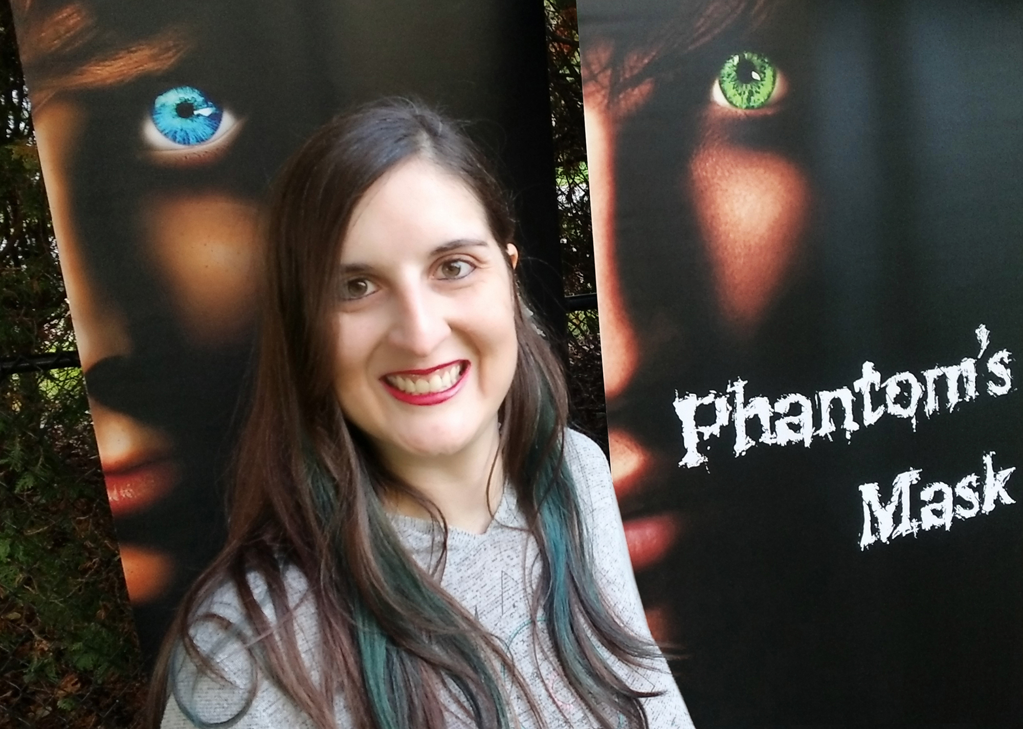 Author Sara A. Noe in front of A Fallen Hero and Phantom's Mask book covers