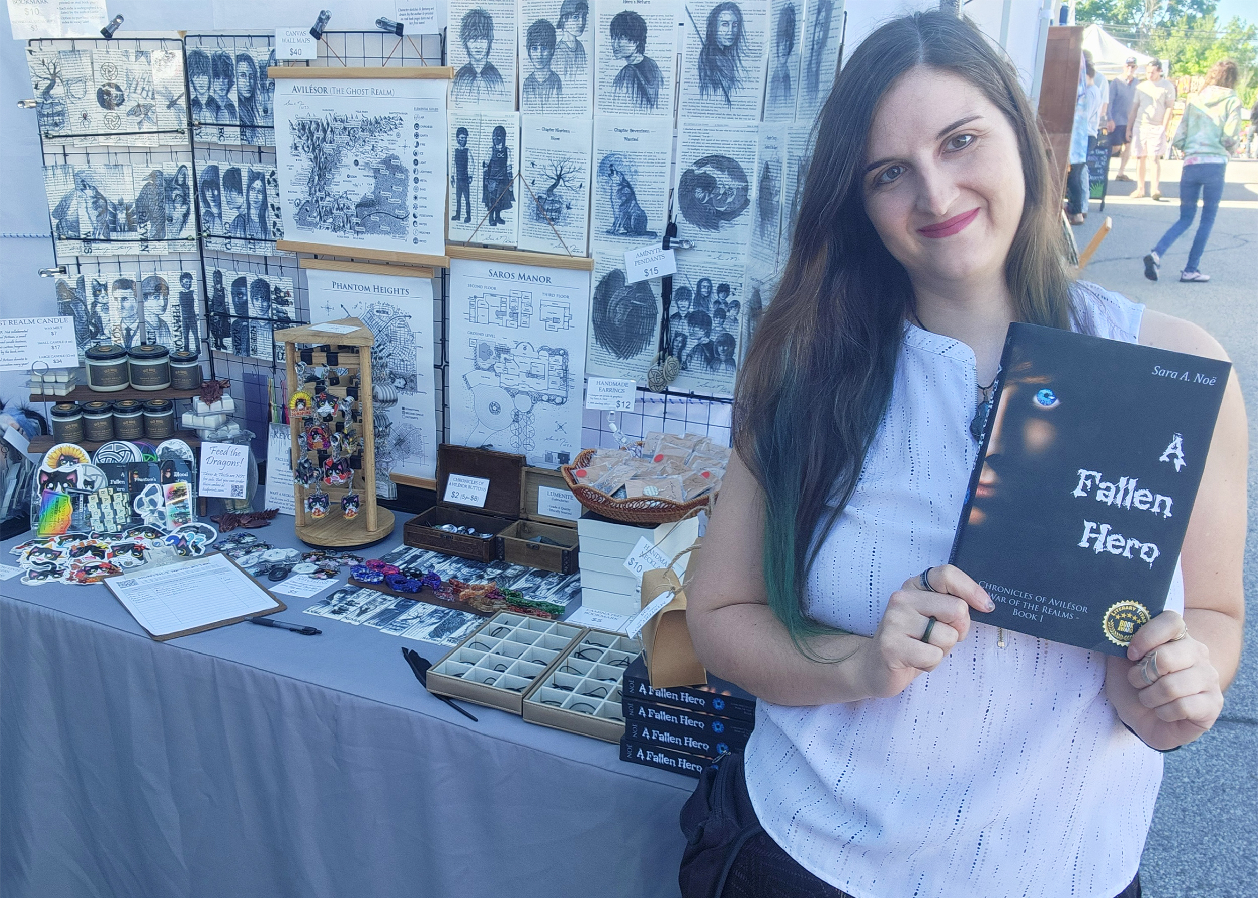 Author Sara A. Noe holding A Fallen Hero in front of her booth