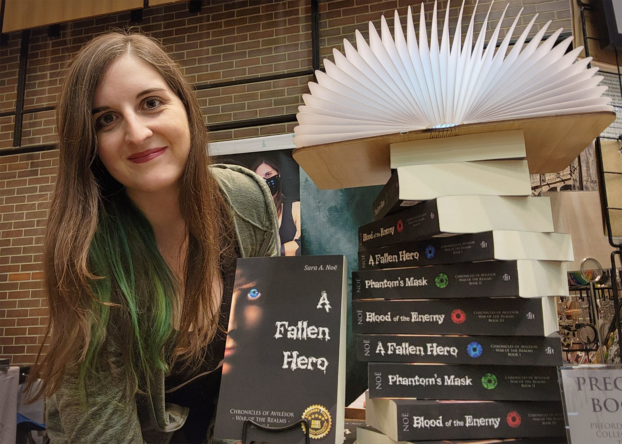 Author Sara A. Noe by a stack of the Chronicles of Avilesor book series at an event